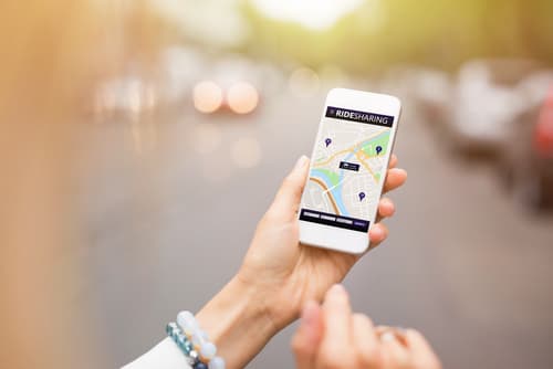 person standing near the street using rideshare app