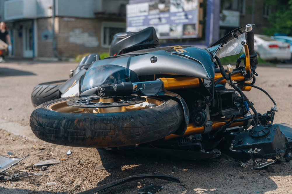 A damaged motorcycle lying on the road after a severe collision. Close-up view of the aftermath of a traffic accident, with visible damage to the bike.