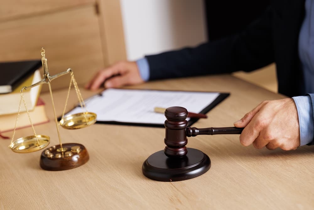 Lawyers or judges sign documents under fair legal terms, emphasizing ethics, integrity, and justice, with the balance of law represented by the gavel.