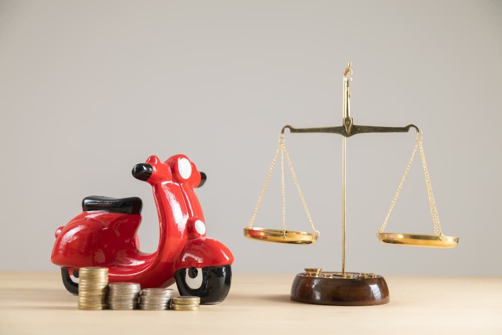 Close-up of a red motorbike piggy bank alongside scales and money.