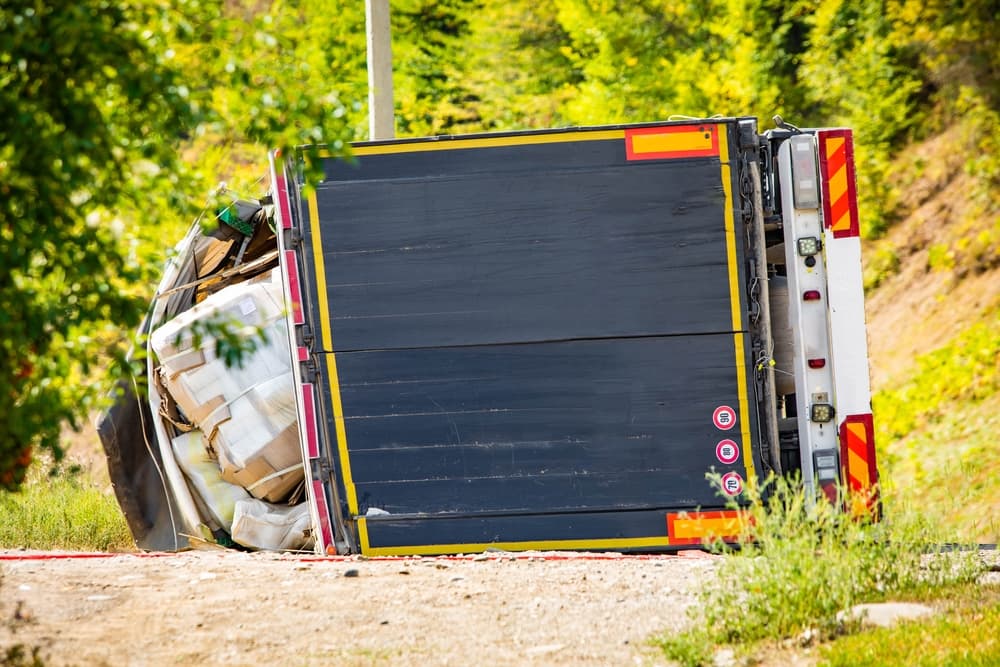 A large cargo truck overturned on the road after a daytime traffic accident.