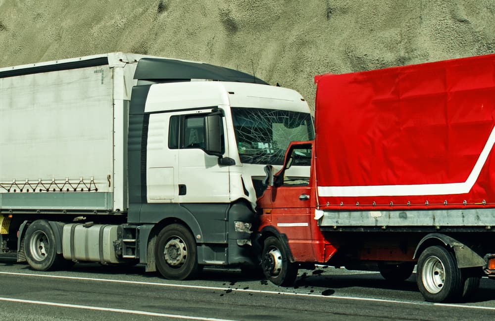 Collision between two trucks on the road, resulting in a frontal impact.